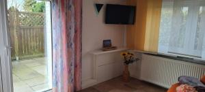 a living room with a television and a vase of flowers at Ferienwohnung im Leuchtturmort Bastorf in Bastorf