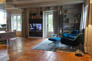 a living room with blue chairs and a television at Reethus Haupthaus im EG OG in Borgsum