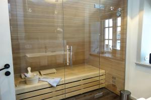 a shower with a glass door in a bathroom at Reethus Haupthaus im EG OG in Borgsum +12 photos