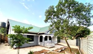 a white house with a green roof at Paradise Pathways Lweza in Kampala