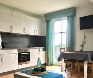 a kitchen with white cabinets and a table and a window at Gästehaus Frankenwaldhof in Bad Steben