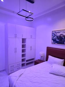 a bedroom with a white bed and white cabinets at BJ Home in Iseri-Oke