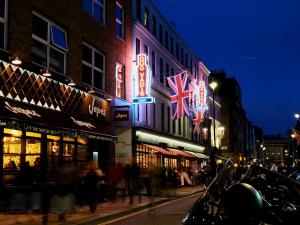 a city street at night with neon signs at Otherwander Soho Pod Hotel in London