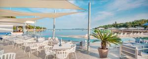 a restaurant with white tables and chairs and the ocean at Easyatent Mobile home Lanterna in Poreč +22 photos
