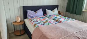 a bed with a blue headboard and pillows at Ferienwohnung im Leuchtturmort Bastorf in Bastorf
