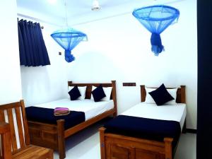 zwei Betten in einem Zimmer mit blauen Lichtern an der Wand in der Unterkunft Natraj Guest House in Trincomalee