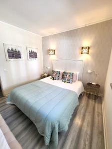 a bedroom with a white bed with a blue blanket at Beachome4u in Carcavelos