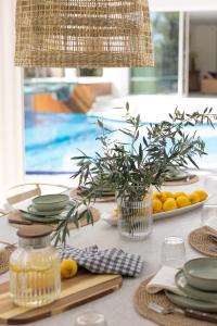 a table with plates and bowls and a vase of flowers at Villa Stefani with Private Pool in Athens