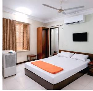a bedroom with a large white bed with an orange blanket at Hotel amrit in Indore