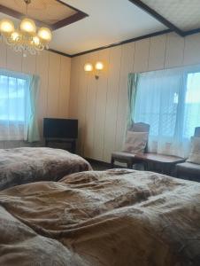 a bedroom with two beds and a chair and windows at 波松の家 in Awara