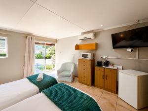 a bedroom with two beds and a tv on the wall at 12 On Churchill in George