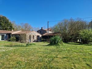 a house in a yard with a grass field at La Maison Des Landes in Mouzillon