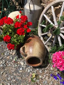 a flower arrangement of red flowers next to a wheel at Pinabre Rose Cottage in Plouguenast Langast +4 photos