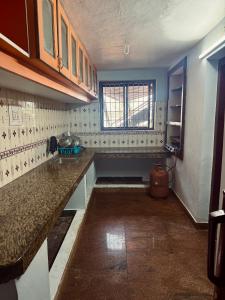 an empty kitchen with a counter and a window at Stay by the Backwater in Kalyānpur