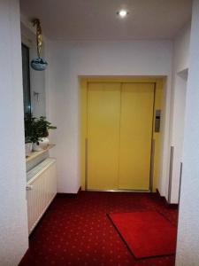 eine gelbe Tür in einem Zimmer mit einem roten Teppich in der Unterkunft Hotel Goldbächel in Wachenheim an der Weinstraße