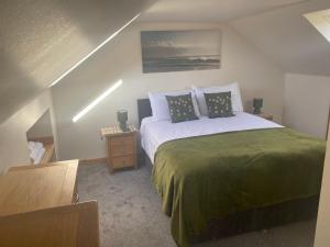 a bedroom with a large bed with a green blanket at Skye Getaways Self Catering Accommodation in Dunvegan
