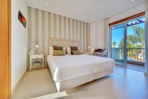 a bedroom with a large white bed and a balcony at Villa Magnolia The Crest 3 quartos e piscina in Almancil +21 photos