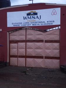 a red building with a garage with a sign on it at WMSAJ HOMEs in Narok