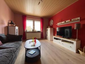 a living room with a couch and a tv at Ferienhaus Soonwald in Schwarzerden