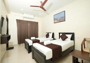 a hotel room with two beds and a ceiling fan at ADITYA BEACH SUITES in Visakhapatnam +19 photos