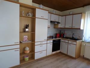 a kitchen with white cabinets and wooden shelves at Ferienhaus Soonwald in Schwarzerden +9 photos