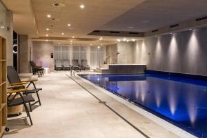 ein großer Swimmingpool in einem Raum mit Tischen und Stühlen in der Unterkunft Hotel Helios in Lipová-lázně