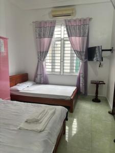 a bedroom with two beds and a window at Nhà nghỉ thảo chung in Kỳ Lừa