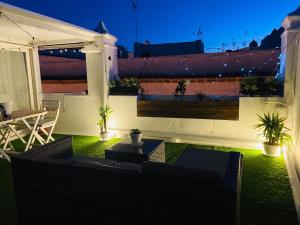 a patio with a couch and a table on a roof at Ático Cádiz Suite in Cádiz