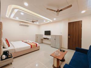 a bedroom with a bed and a couch and a tv at Hotel Sunrise N Resorts in Nagpur