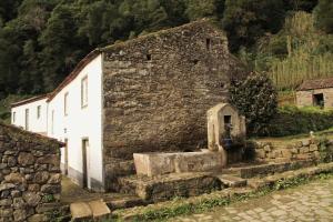 an old stone building in front of a house at Aldeia do Sanguinho in Faial da Terra +13 photos