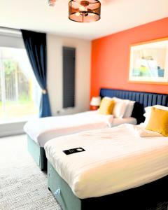 two beds in a room with orange walls at Haslar Rooms in Gosport