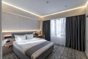 a hotel room with a bed and a large window at Renion Almaty Hotel in Almaty