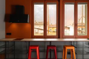 a counter with three red stools in a room with windows at Le Stanze Di Vittoria in Cesenatico
