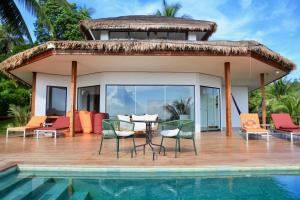 a patio with a table and chairs next to a pool at House of Rising Sun in Thong Nai Pan Noi