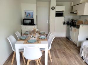 a dining room with a white table and white chairs at Villa Chez Laurette - Baie de Somme en famille - 4 à 6 personnes - piscine - parking privé - plage à 5 min in Le Crotoy
