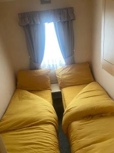 two beds in a small room with a window at KC Caravans in Ingoldmells