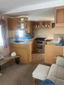 a small kitchen with wooden cabinets and a couch at KC Caravans in Ingoldmells