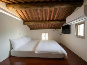 a bedroom with a white bed with a wooden ceiling at Zhong Lan Homestay in Chung-lan