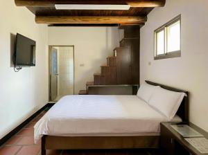 a bedroom with a bed and a tv and stairs at Zhong Lan Homestay in Chung-lan +2 photos