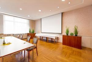 a conference room with tables and chairs and a projection screen at Hotel Wartburg in Stuttgart