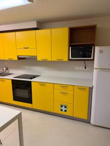a kitchen with yellow cabinets and a white refrigerator at Hobeda 6 Guest House in Tallinn