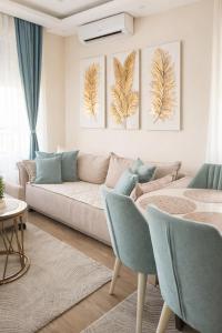 a living room with a couch and three paintings on the wall at Panorama GOLD Vrnjačka Banja in Vrnjačka Banja