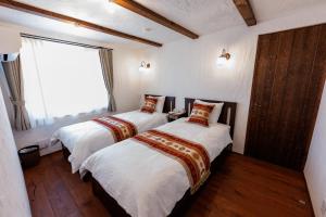 two beds in a room with a window at Villa Ferme Yatsugatake in Hokuto
