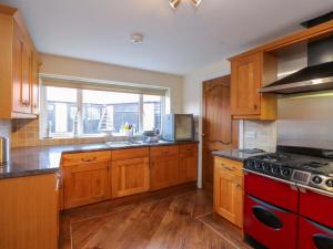 a kitchen with wooden cabinets and a red stove top oven at The Old Stables in Colwyn Bay