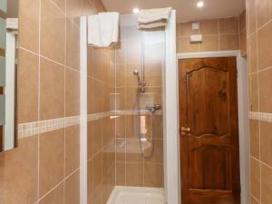 a bathroom with a shower with a wooden door at The Old Stables in Colwyn Bay +19 photos
