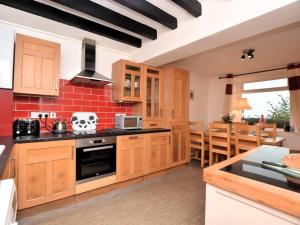 a kitchen with wooden cabinets and a red brick wall at 3 Bed in Conwy oc-85844 in Llanbedr-y-cennin