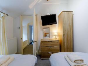 a bedroom with two beds and a dresser with a television at 3 Bed in Conwy oc-85844 in Llanbedr-y-cennin