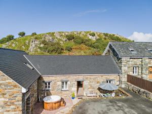 an exterior view of a stone house with a hot tub at 2 Bed in Arthog oc-43105 in Arthog
