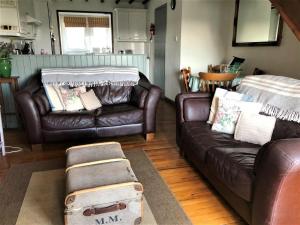 a living room with two leather couches and a suitcase at 2 Bed in Conwy oc-tycan in Llangelynin