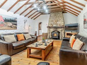 a living room with leather furniture and a stone fireplace at 3 Bed in Swansea oc-93942 in Ilston